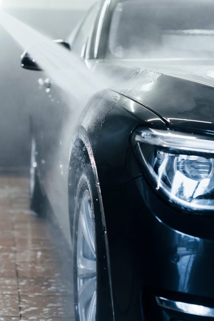 high pressured water modern black automobile get cleaned inside of car wash station